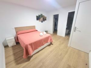 ein Schlafzimmer mit einem Bett mit einer rosa Decke und einem Holzboden in der Unterkunft Vivienda El Viajero in Valverde