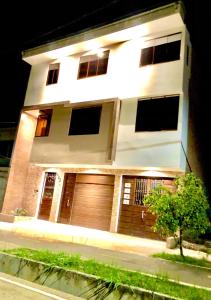 a white house with a wooden garage door at night at CASA SHILCAYO Habitaciones Vacacionales in Tarapoto