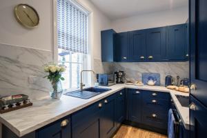 een keuken met blauwe kasten en een klok aan de muur bij Cosy 2 bedroom Cottage in a World Heritage Village in Shipley