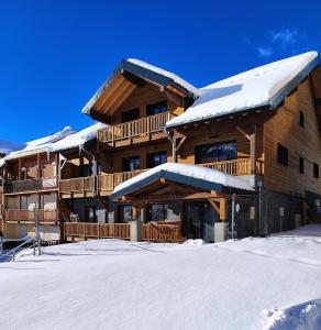 ein großes Holzgebäude mit Schnee darauf in der Unterkunft Chalet Le Bouquetin in Saint-François-Longchamp