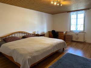 a bedroom with a bed and a desk and a window at charmante 3,5 Zimmer Wohnung in Bauernhaus in Volketswil