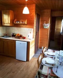 a kitchen with a table and a white refrigerator at Domki przy plaży 80 m Jantar w Gąskach in Gąski