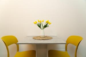 a table with a vase with yellow flowers on it at Affittacamere A casa di Serena in Ancona
