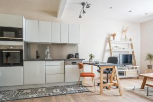 cocina con armarios blancos, mesa y sillas en Appartement Maurice - Welkeys en Montrouge
