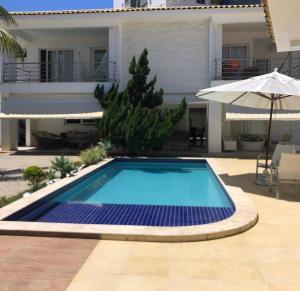 een zwembad voor een huis met een parasol bij Casa Villas in Lauro de Freitas