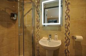 y baño con lavabo y ducha con espejo. en Central House, en Shillelagh