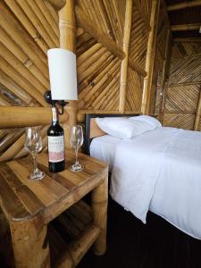 1 dormitorio con 1 cama y 1 botella de vino en una mesa en GOLDEN TREE MINDO ECO-LODGE, en Mindo
