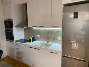a kitchen with white cabinets and a stainless steel refrigerator at Regal Comfort Apartment in Pirot