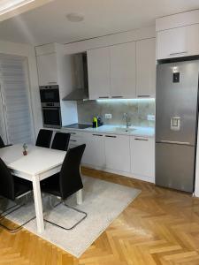 a kitchen with a table and chairs and a refrigerator at Regal Comfort Apartment in Pirot