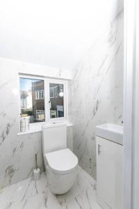 een witte badkamer met een toilet en een raam bij Modern and Luxury House for 8 in Gillingham