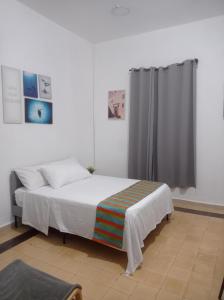 1 dormitorio con cama blanca y cortina en Hostal Mi Rincón, en Santo Domingo