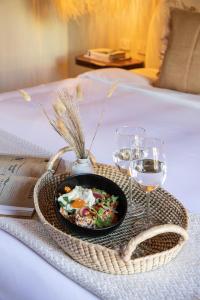 een dienblad met een bord eten en wijnglazen op een bed bij HOLT Hotel del Pueblito in San Miguel de Allende
