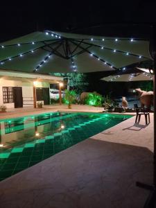 a swimming pool at night with an umbrella at finca campestre las heliconias in Puerto Triunfo