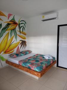 uma cama num quarto com uma pintura na parede em finca campestre las heliconias em Puerto Triunfo