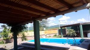 a house with a swimming pool with a wooden roof at Casa de campo El Ceibal in Salta