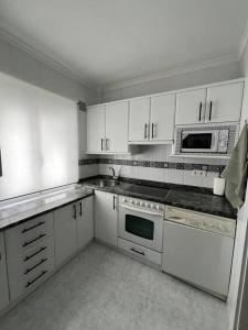 een keuken met witte kasten en witte apparaten bij Piso acogedor cerca del centro. in Burgos