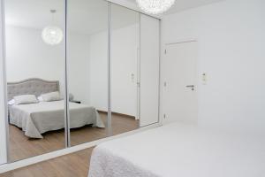 a white bedroom with a bed and a mirror at Villa Santiago in Praia