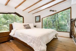 a bedroom with a bed and two large windows at Casa de la Selva-Jungle Getaway with cenotes in Playa del Carmen