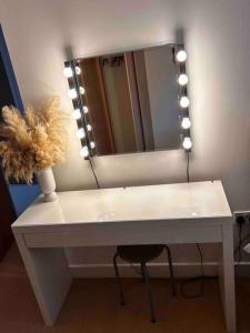 uma mesa branca com um vaso e um espelho em City Centre apartment. em Wrexham