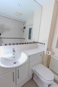 a white bathroom with a sink and a toilet at Spacious and Luxurious 5 Bedroom Town House for 9 in Kent