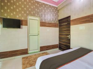 1 dormitorio con 1 cama y TV de pantalla plana en Collection O Hotel Paradise And Restaurant, en Kāshīpur
