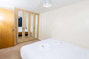 a bedroom with a white bed and a mirror at Spacious and Luxurious 5 Bedroom Town House for 9 in Kent