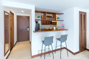 uma cozinha com duas cadeiras e um bar num quarto em Leblón Suites Hotel em Medellín