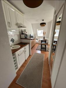 uma cozinha com armários brancos, um lavatório e uma mesa em Studio cocooning petite vue mer em Cabourg
