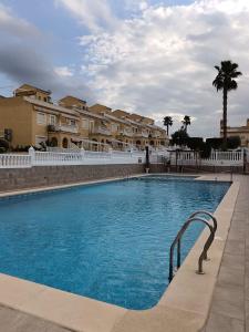 a large blue swimming pool with buildings in the background at Bungalow Gran Alacant in Gran Alacant