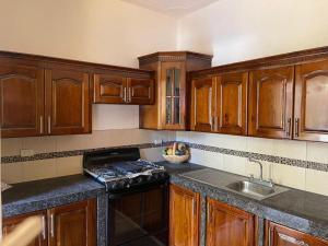 a kitchen with wooden cabinets and a stove and a sink at Puerto Vallarta casas vacacionales in Puerto San José