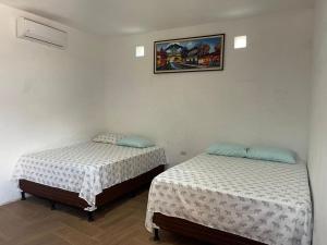 two beds in a room with a picture on the wall at Puerto Vallarta casas vacacionales in San José de Guatemala