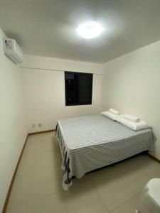 a bedroom with a bed in a white room at Quarto c/Ar, sala, cozinha, banheiro, garagem 24h. in Salvador