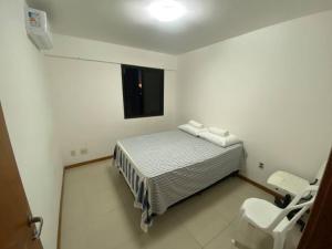 a small white room with a bed and a window at Quarto c/Ar, sala, cozinha, banheiro, garagem 24h. in Salvador