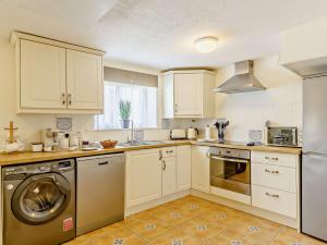 een keuken met witte kasten en een wasmachine bij 3 Bed in Umberleigh 65851 in Atherington