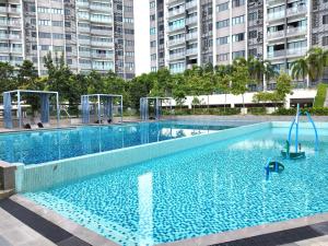 una grande piscina blu con alti edifici sullo sfondo di Puchong WindyLakeViewStayCation3R2B AT D Island a Puchong