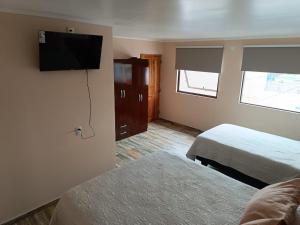 a hotel room with two beds and a flat screen tv at Cafetto Hostal in Caldera