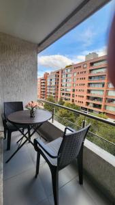 een balkon met een tafel en stoelen en uitzicht op een gebouw bij invitin annabella's apartment in Quito