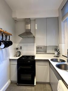 a kitchen with a black stove and a sink at Quaint 1BD Flat 5 mins from Emirates Stadium! in London