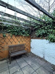 a wooden bench sitting under a wooden pergola at Quaint 1BD Flat 5 mins from Emirates Stadium! in London