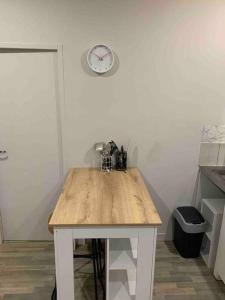 una mesa de madera en una cocina con reloj en la pared en Chez Maryline-joli T2 spacieux en Villeurbanne