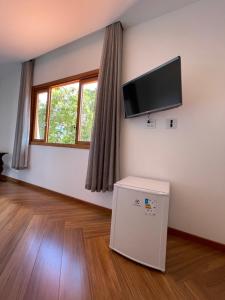un soggiorno con TV a schermo piatto a parete di Suítes no Paraíso a Espera Feliz