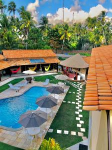 ein Resort mit einem Pool mit Sonnenschirmen und Stühlen in der Unterkunft Pousada Yapara-Tyba in Japaratinga