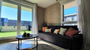 - un salon avec un canapé et une grande fenêtre dans l'établissement Logement moderne et lumineux Terrasse et Parking, à Caen