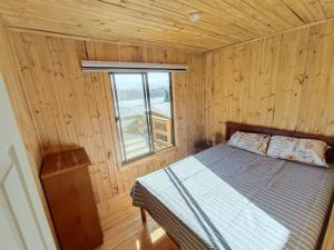 1 dormitorio con 1 cama en una cabaña de madera en Cabaña vista Lago Vichuquen, en Vichuquén