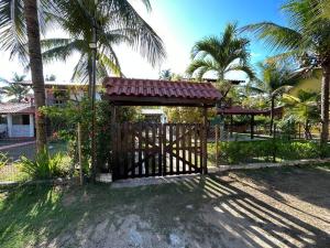 a wooden gate in a yard with palm trees at Casa de praia pé na areia: nos braços da natureza. in Ilhéus