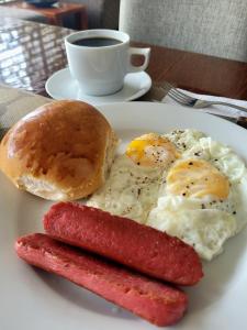 un plato con huevos y salchichas y un bagel y una taza de café en Murano Hotel en Moyobamba