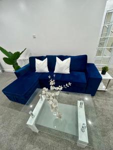 a blue couch in a living room with a table at Cosy 3 bedroom Near Heathrow - 6 beds, sleeps 7, FREE PARKING in Staines upon Thames