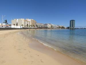 a sandy beach with buildings in the background at Casahost Guenia Beach Apartment in Arrecife
