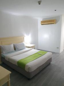 een slaapkamer met een bed met een groene deken erop bij SAB R.CONDOTEL and room rental in Manilla
