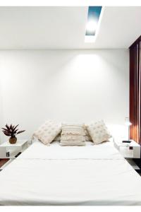 a bedroom with a white bed with two white tables at Bello apartamento en Equipetrol in Santa Cruz de la Sierra